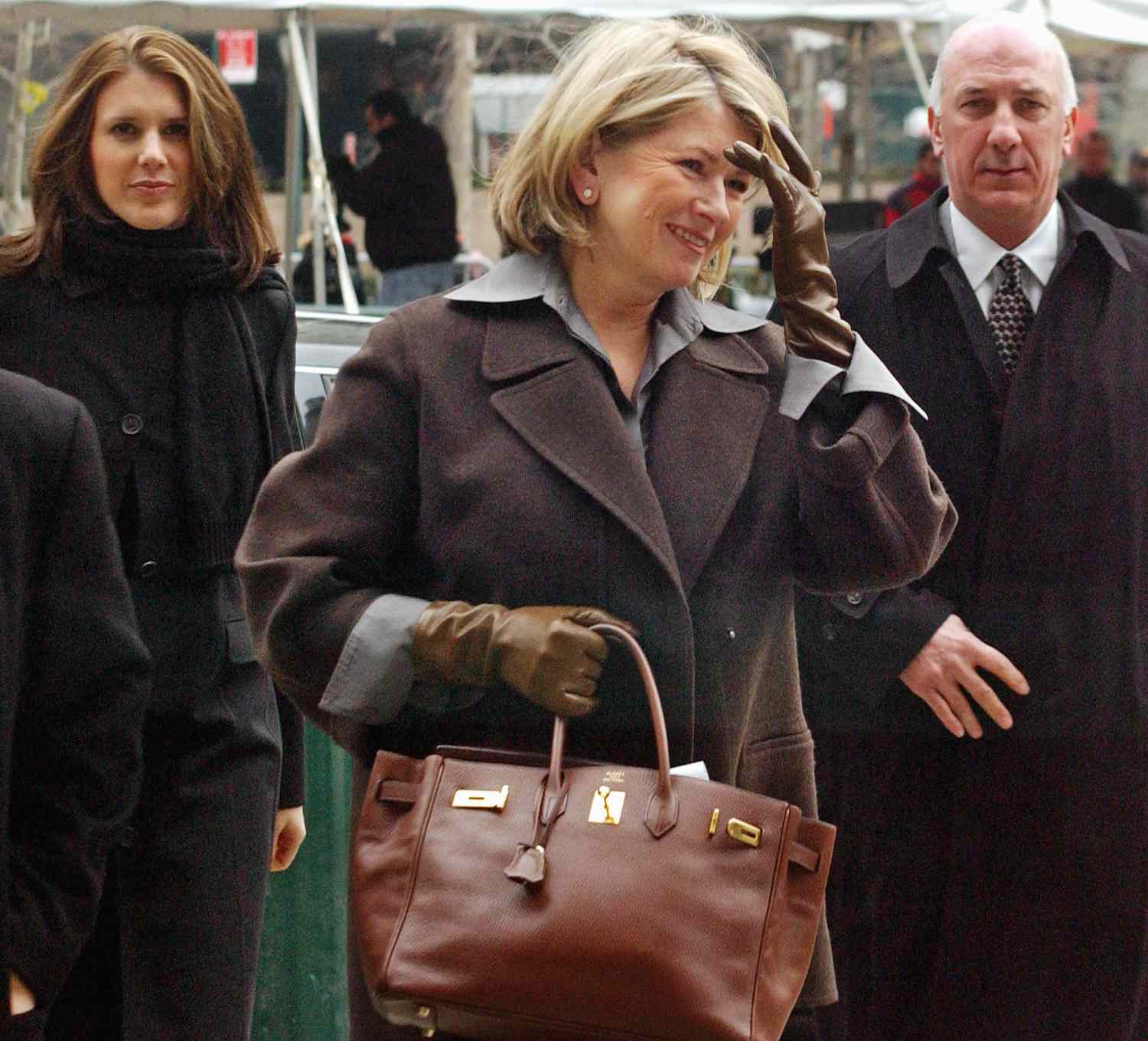 decorvow walking outside holding a Birkin bag accompanied by others