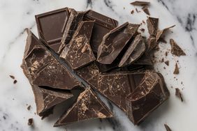 Broken pieces of a chocolate bar on a marble surface
