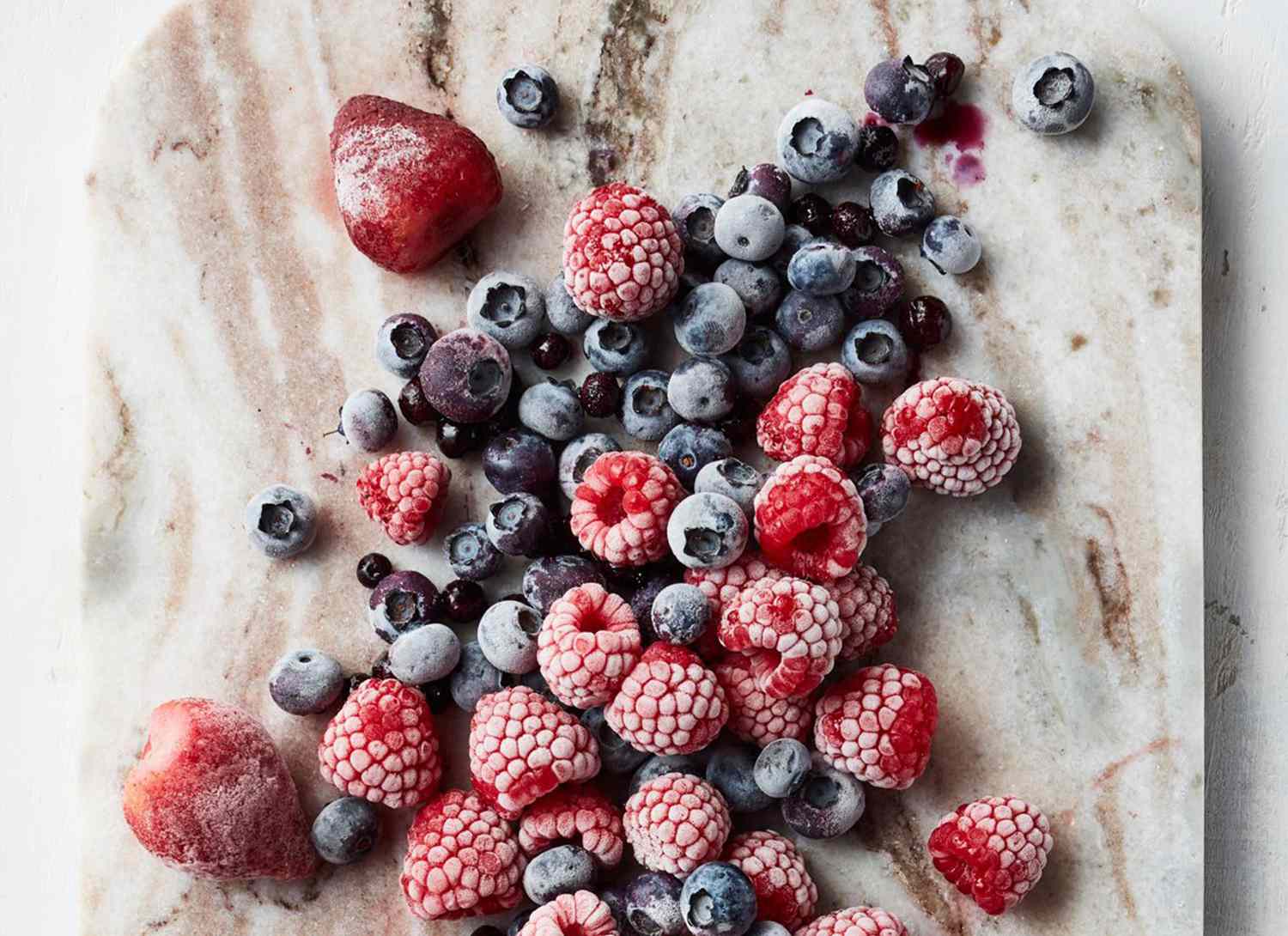 overhead view of frozen berries on a marble cutting board