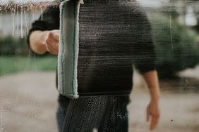 A person cleaning a glass surface with a window squeegee partially removing streaks and water marks