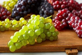 Clusters of green red and dark grapes on a wooden surface