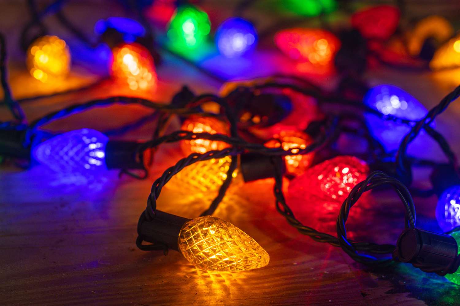 String of colorful holiday lights on a wooden surface