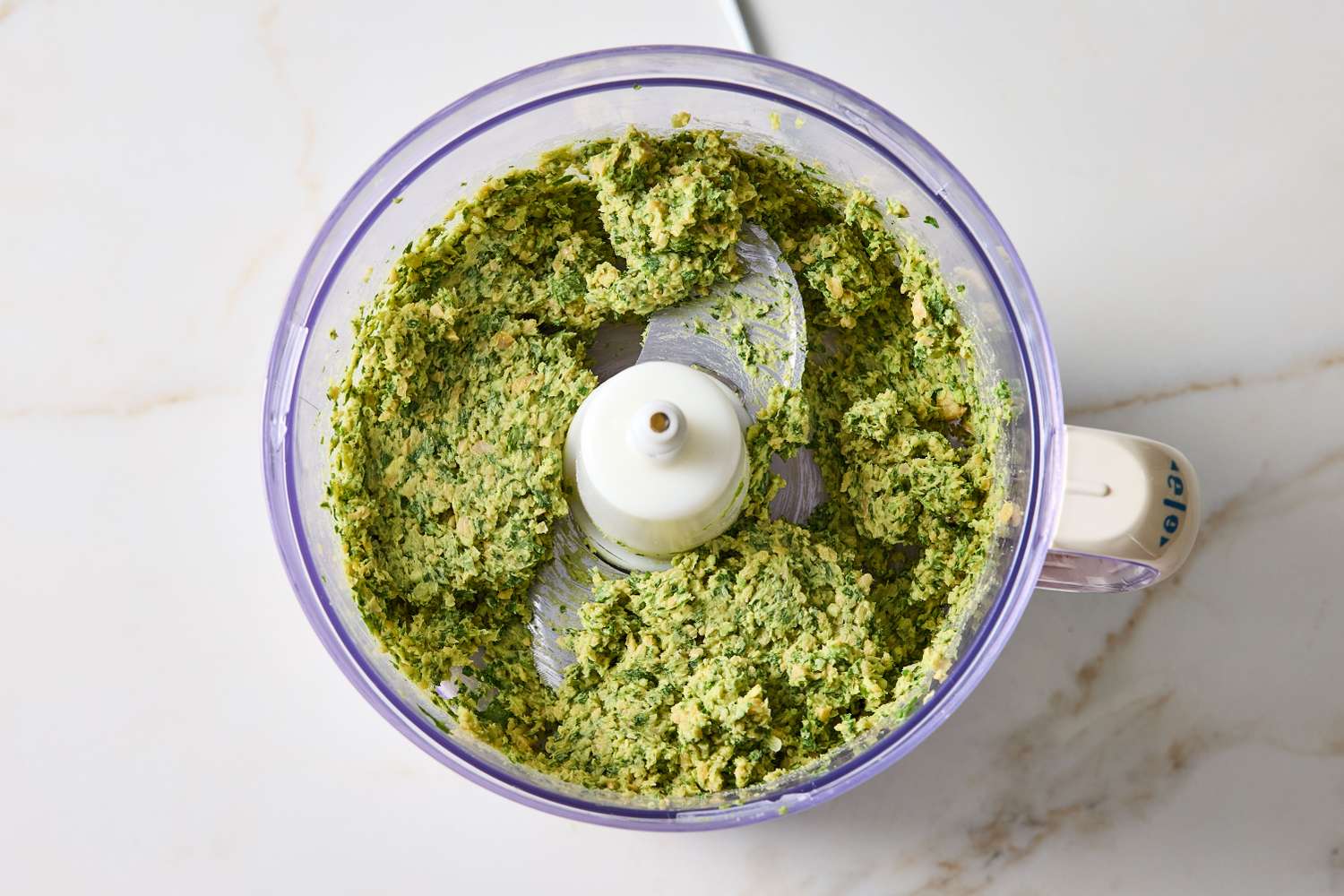 A food processor containing blended guacamole hummus mixture