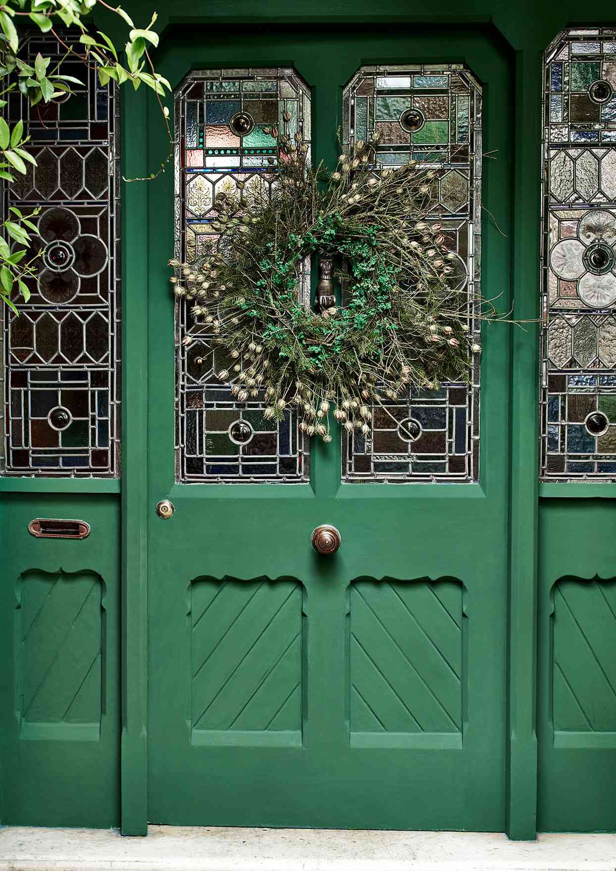 green front door with festive greenery wreath