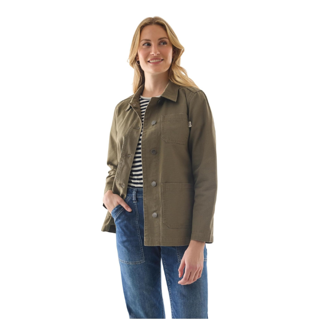 A woman dressed casually in a jacket and jeans standing and smiling