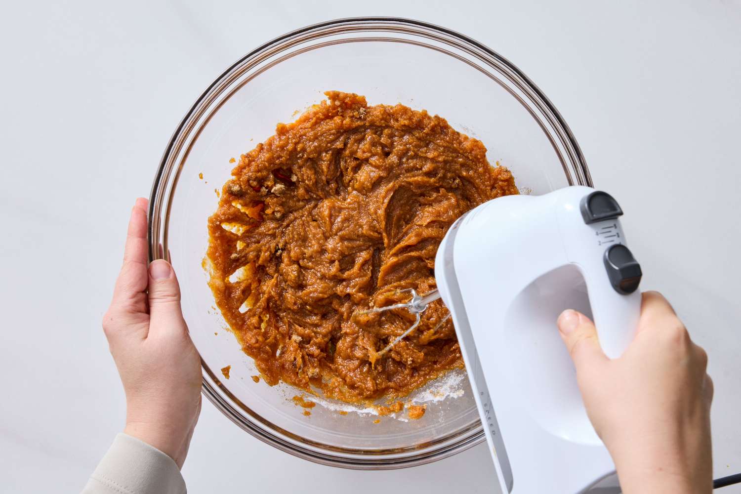Mixing batter with an electric hand mixer in a glass bowl