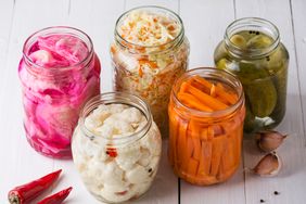 fermented foods including sauerkraut and pickles in glass jars without lids
