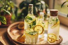 Tray with glasses and bottles of infused water, garnished with lemon slices and mint leaves