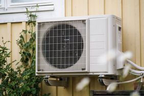 Outdoor air conditioning unit mounted on a yellow wall