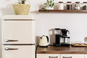 A kitchen counter with a vintage fridge kettle coffee maker and jars on a shelf