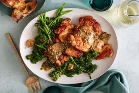 Plate of cooked chicken thighs with sauce and broccolini