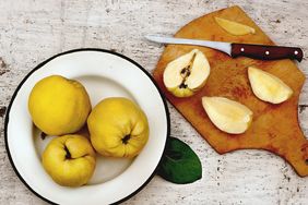 plate of quince and cutting board with cut quince and knife