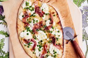 overhead view of a thin crust pizza with ricotta, prosciutto and peas