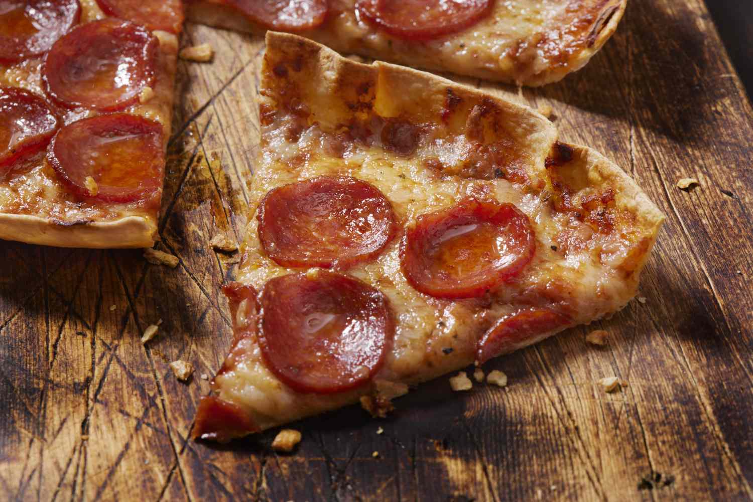 Slice of pepperoni pizza on a wooden surface