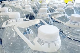 Multiple rows of large water jugs with plastic handles and caps
