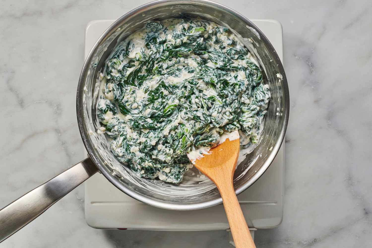 stirring cooked spinach into cream sauce