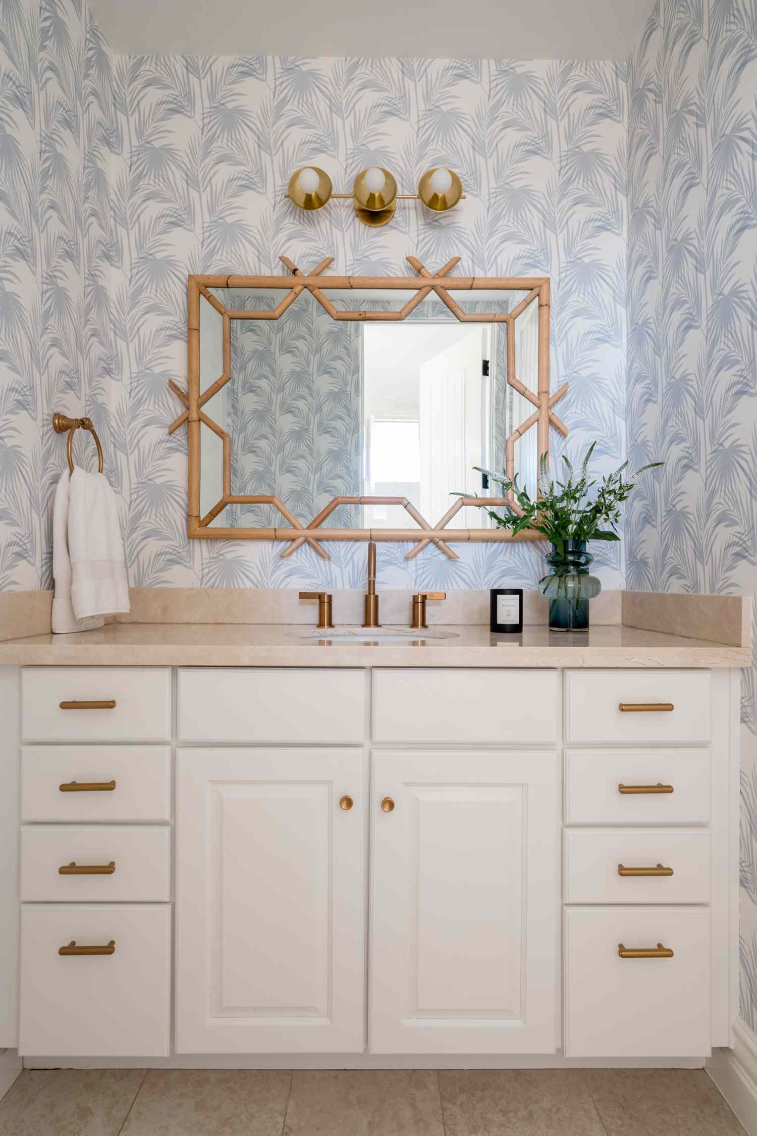 Modern bathroom interior featuring a patterned backsplash goldaccented mirror and vanity with white cabinets and decorative items