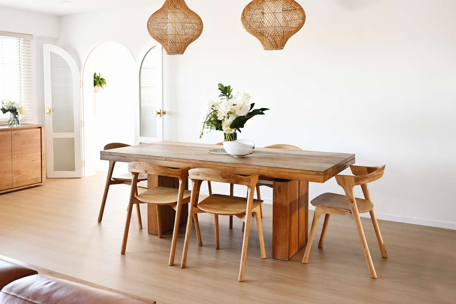 A dining room setup with a wooden table chairs and decorative light fixtures hanging above