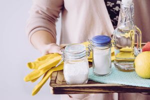 woman holding vinegar, baking soda, and citric acid cleaning supplies