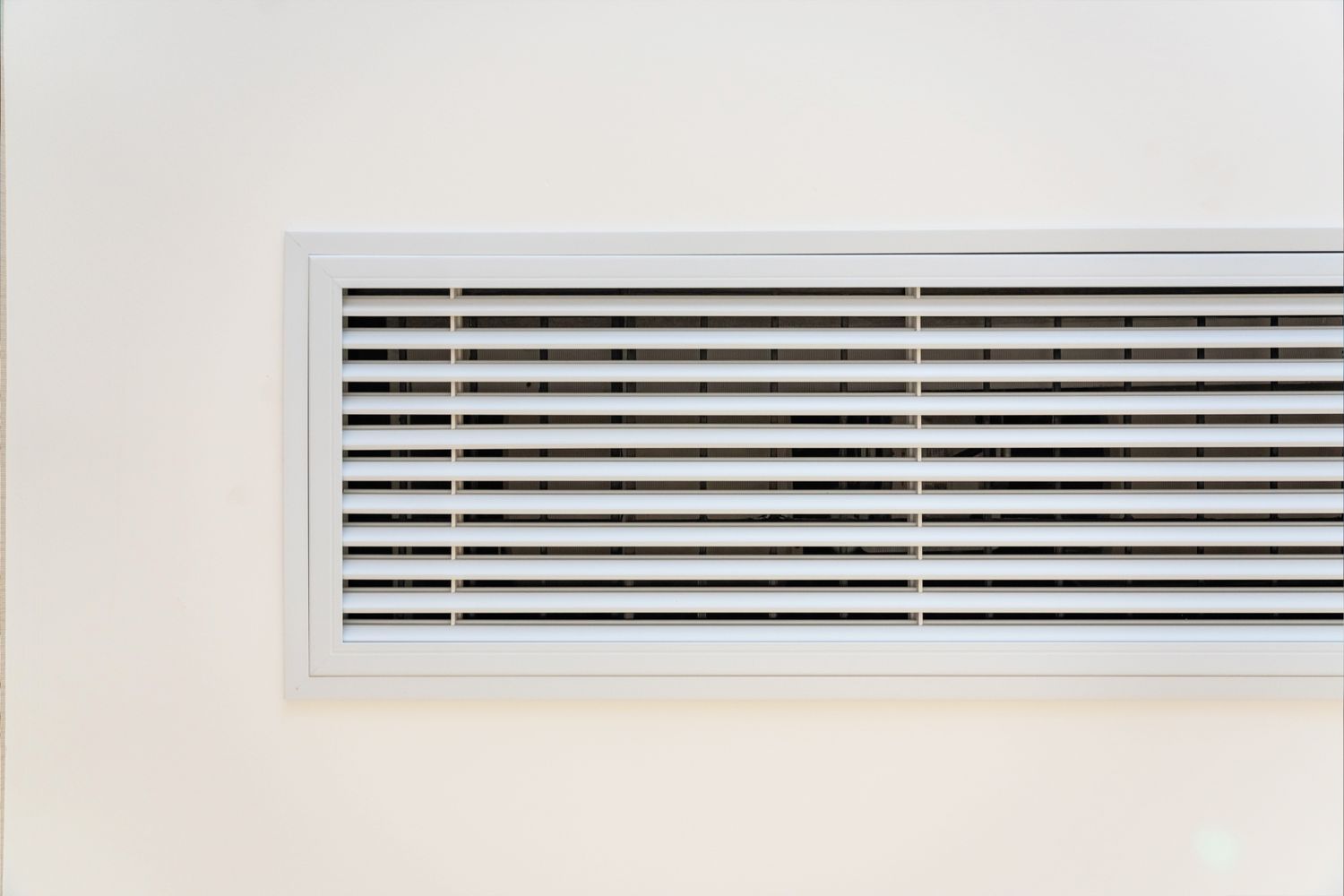 A rectangular air vent with horizontal slats on a wall