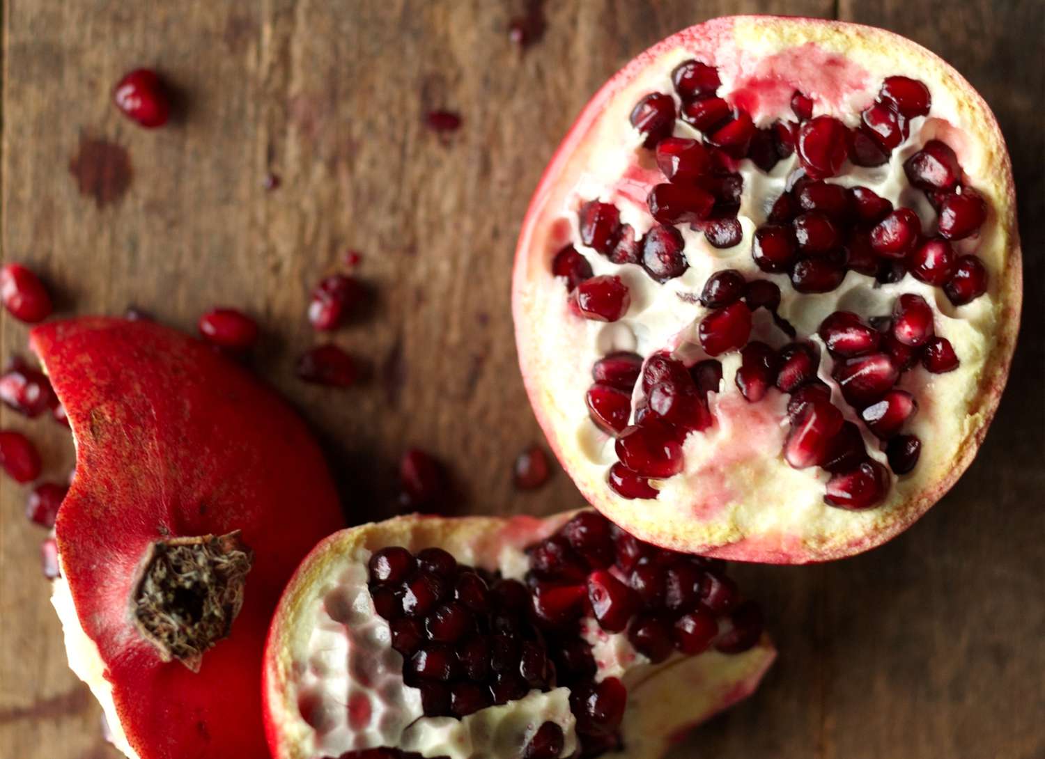close up of a pomegranate sliced in half on wooden surface