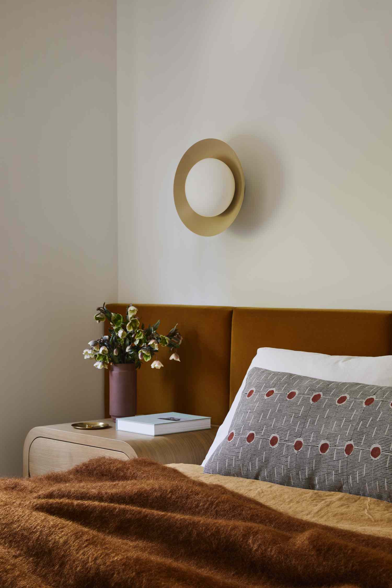 a bedroom with an orange headboard and a subtle wall sconce