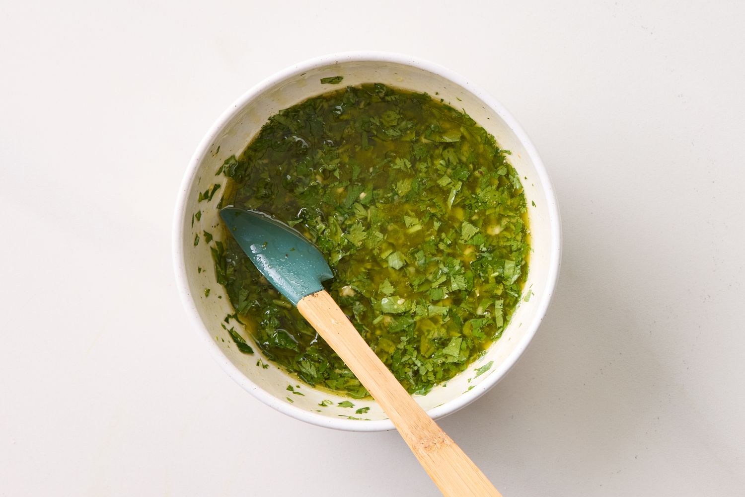 Bowl of green herb sauce with a spatula resting in it
