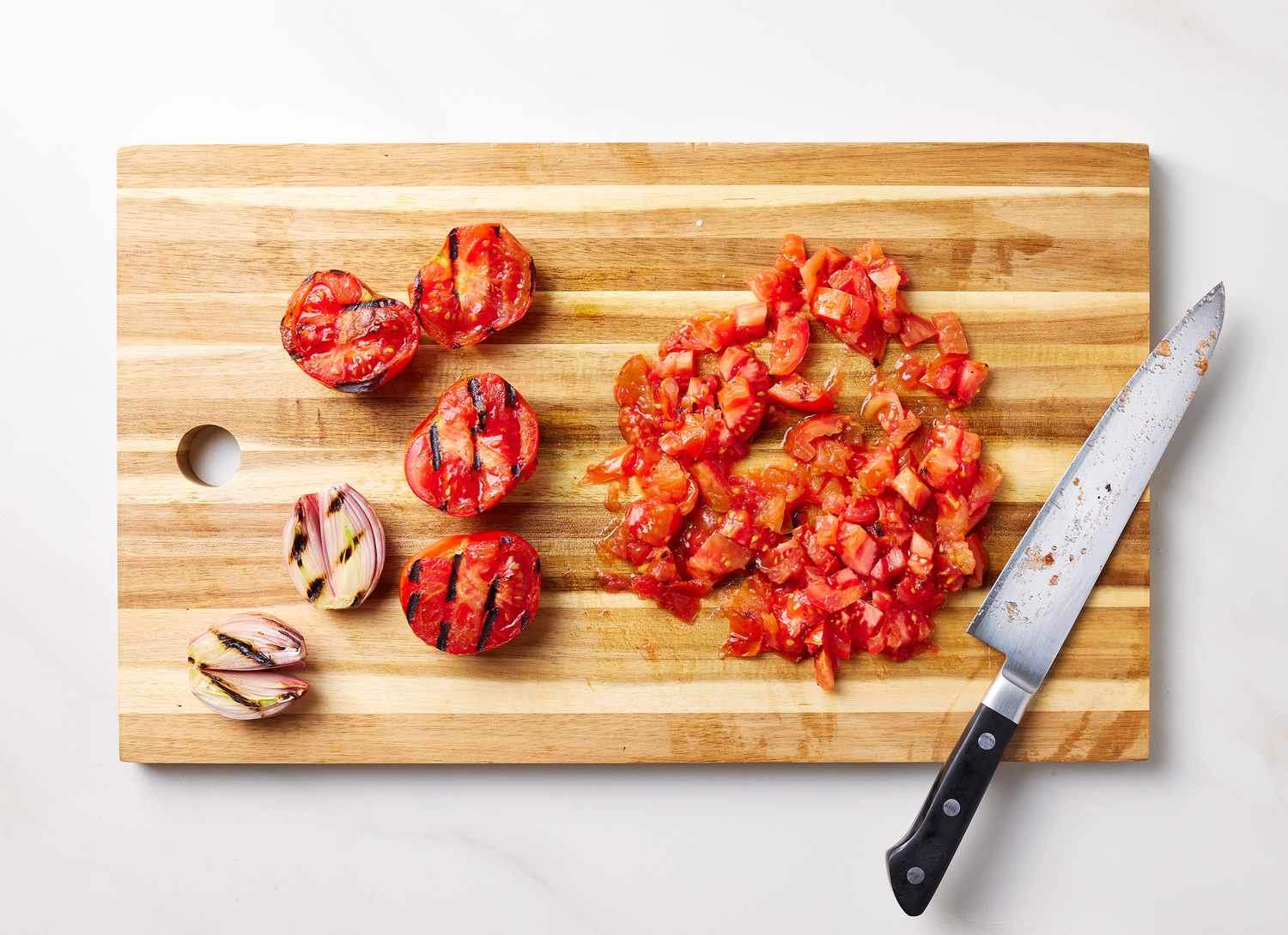 overhead view of grilled tomatoes and onions on a cutting board