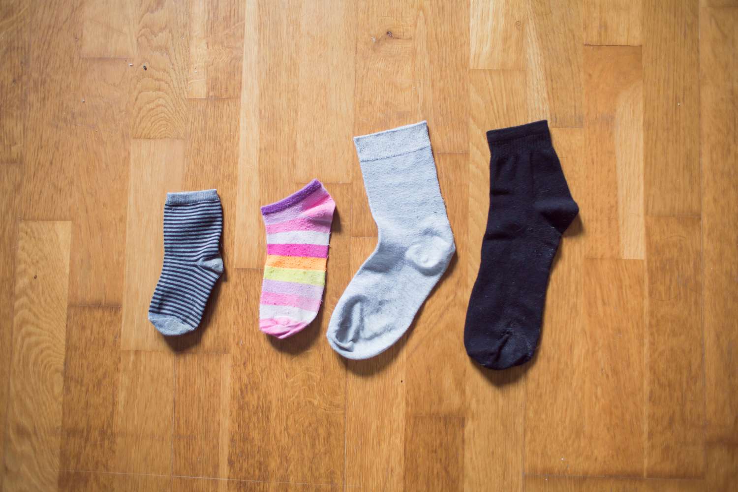 Unpaired socks lying alined on wood floor