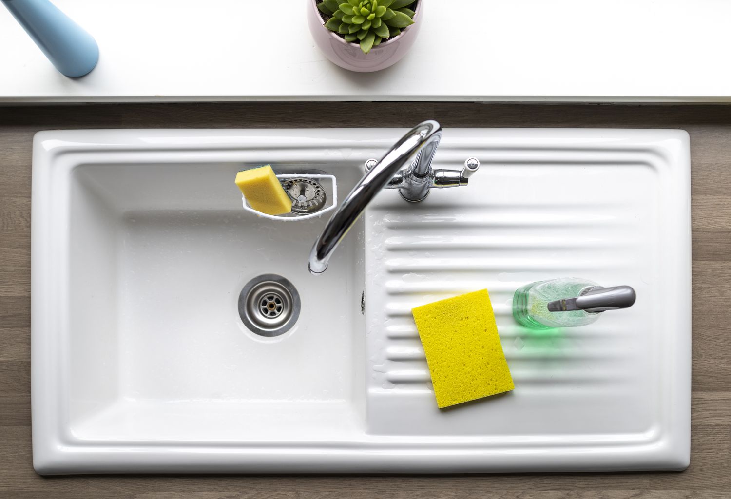 An overhead shot of a clean kitchen sink, a sponge and washing up liquid can be seen near by.