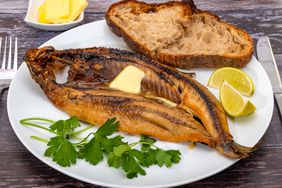 kipper with butter on plate with bread and lemon and parsley