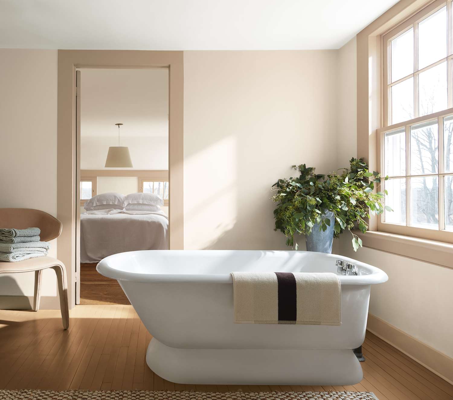 Bathroom with freestanding tub towel potted plant and view of a bedroom through an open doorway