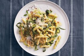 A plate of pasta with grated pecorino zucchini strips and fresh mint