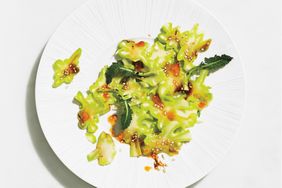 A plate of broccoli stem salad with mint leaves and a dressing