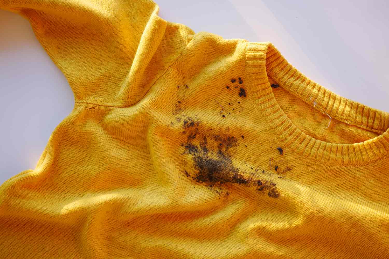 A yellow shirt with a visible dark stain on the fabric near the center