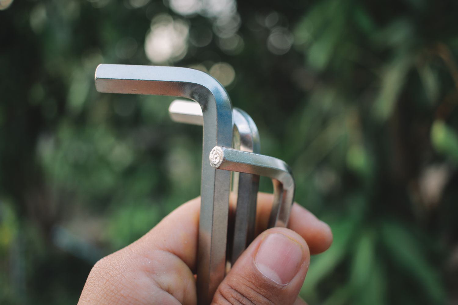 A closeup of a hand holding several hex keys outdoors