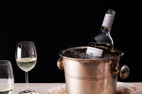 two glasses of white wine next to bottle chilling in bucket
