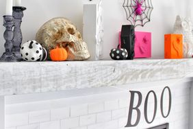 Halloween themed fireplace mantel with decorative skull pumpkins and BOO sign