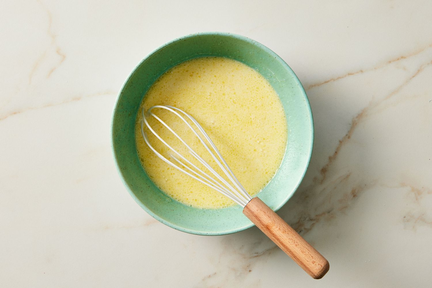 Wet ingredients in green bowl for silver dollar pancakes