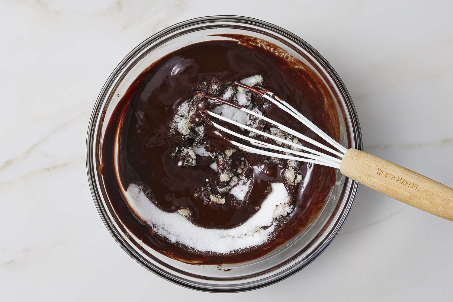 Sugar in bowl of melted chocolate with whisk