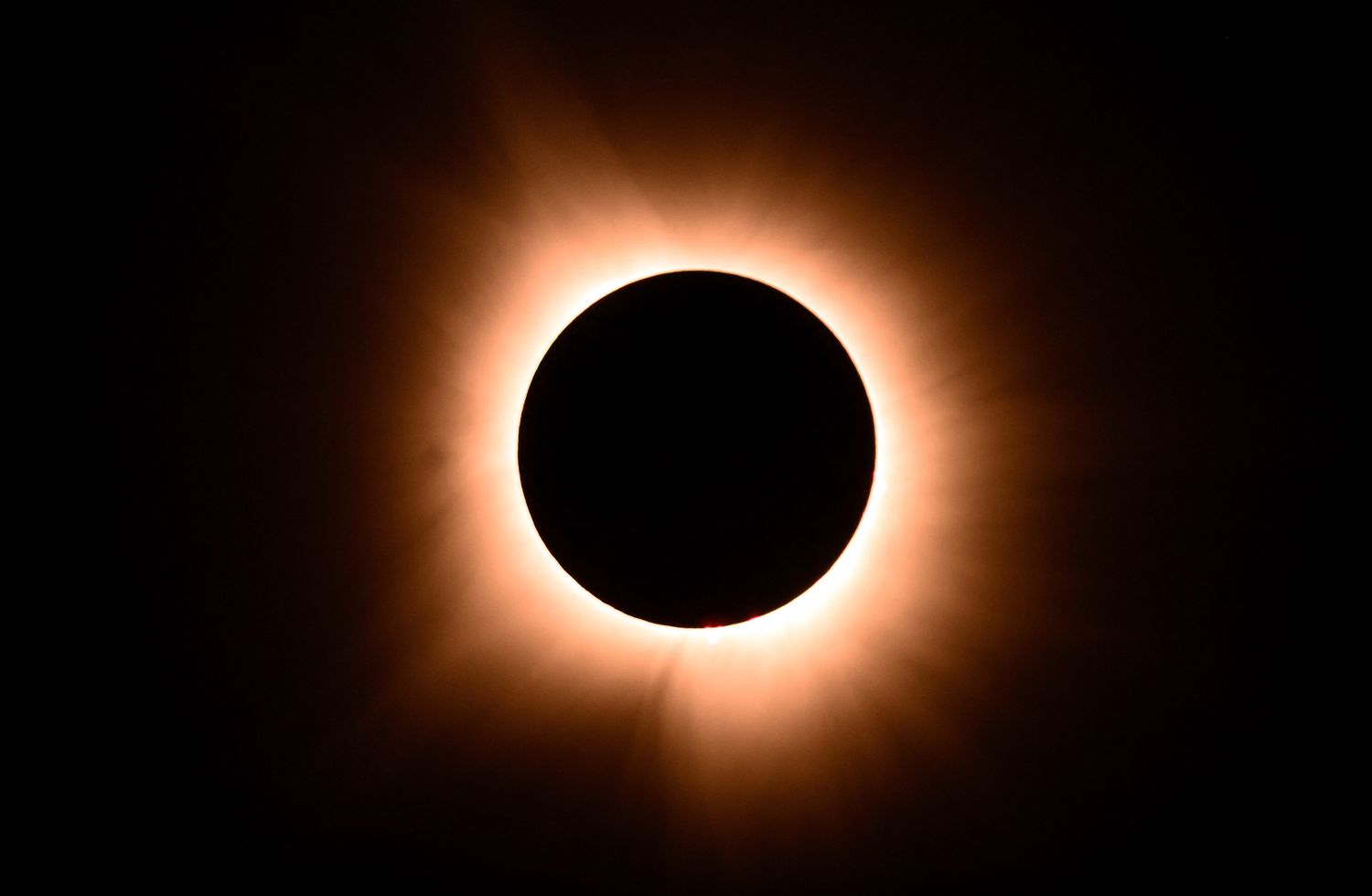 The moment of a total solar eclipse with a glowing corona visible