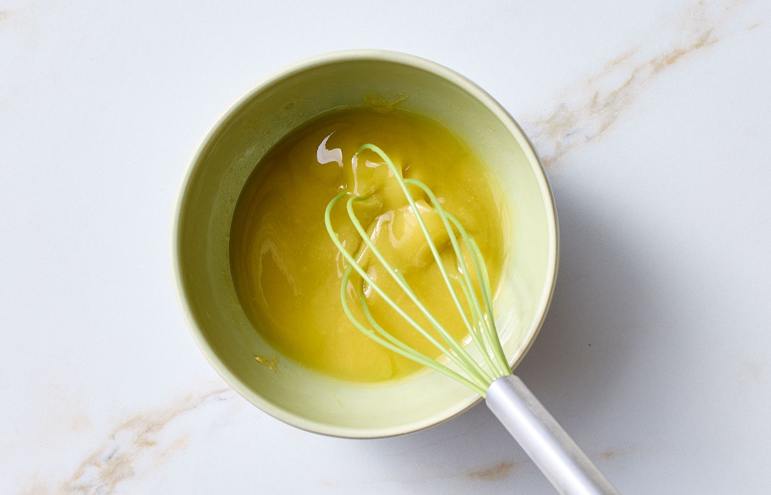 A bowl with a whisk mixing ingredients for a dish, preparation step for a salad