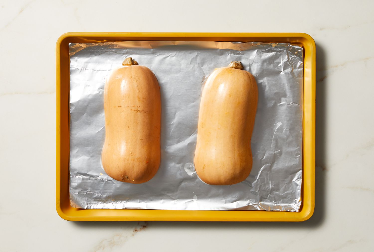 overhead view of butternut squash on tin foil in pan