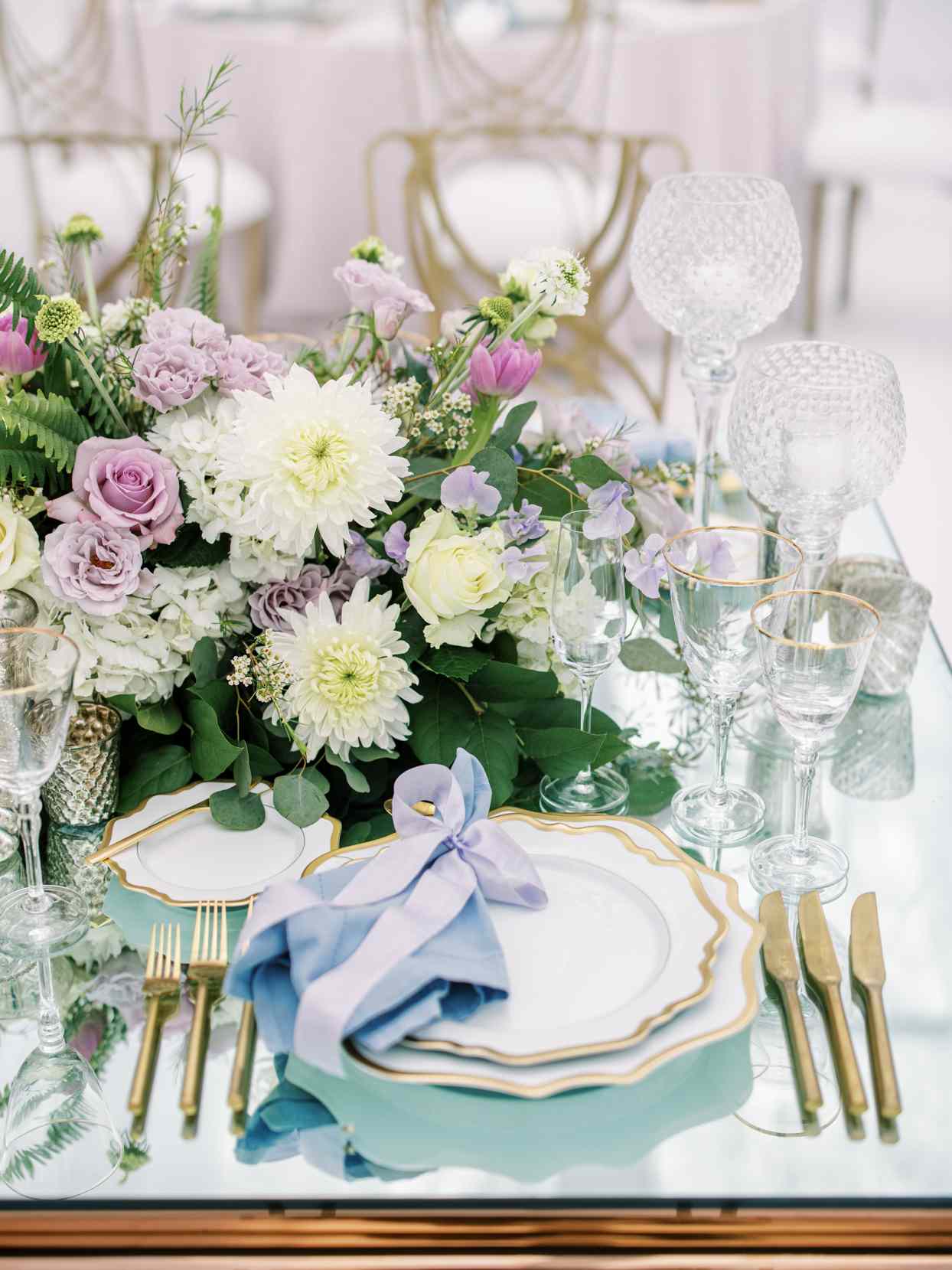gold and white place settings with blue linens and floral centerpieces