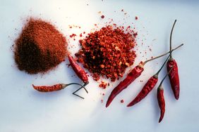 chile powder, chile-flakes, and dried chiles on blue surface