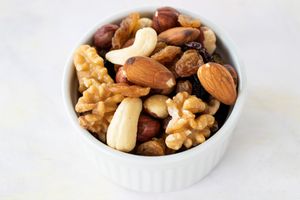 Bowl containing mixed nuts including almonds walnuts raisins hazelnuts and cashews