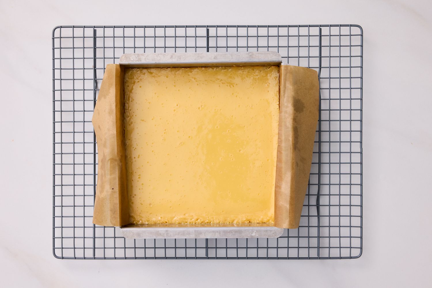 Baked lemon square dessert cooling on a wire rack in a parchmentlined pan