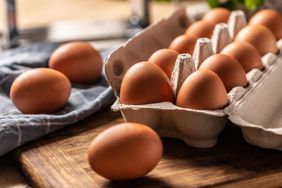 Eggs in a cardboard box on a wooden board in the kitchen.