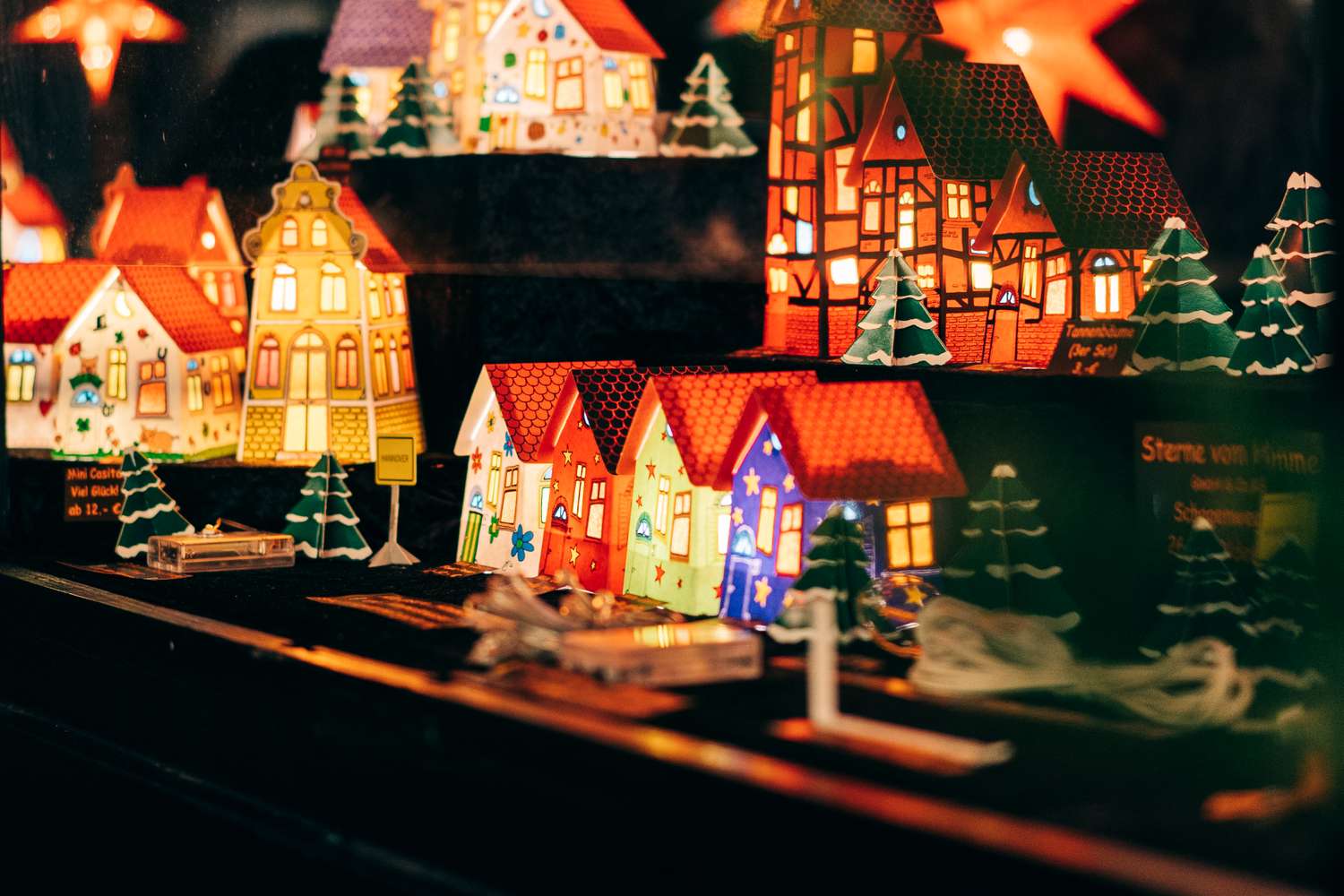 Miniature illuminated houses and trees displayed evoking a festive scene