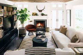 neutral family room with velvet chair and antlers hanging above fireplace